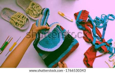 Close up from top view woman hand hold colorful handmade bag from recycle old t shirt on white background, reuse clothes by cut in yarns then crochet to make diy product in leisure activity Foto stock © 