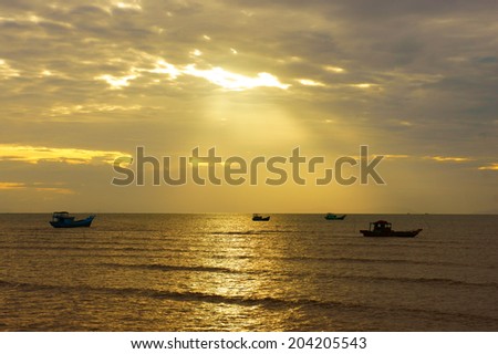Silhouette of group of fishing boat on sea, seascape at sunrise, sky with cloud, sun ray shine on water make beautiful landscape