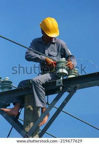 DONG THAP, VIET NAM- SEPT 23:  Asian electrician climb high in pole to work, lineman with cable network, man repair electric post danger and unsafe, is industry service, Vietnam, Sept 23, 2014