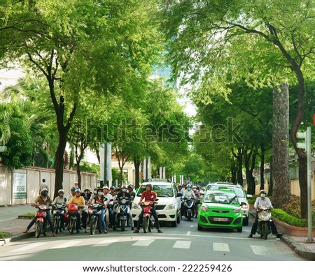 HO CHI MINH CITY, VIET NAM- OCT 7: Fresh air at Asian city, row of  tree on street, crowd of Vietnamese people on motorbike stop on street, group green trees with big trunk, Vietnam, Oct 7, 2014