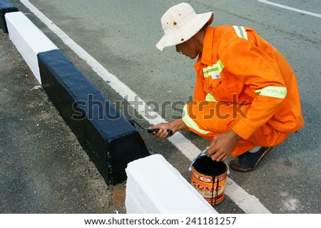 HO CHI MINH CITY, VIET NAM- DEC 30: Asian worker working on street, Vietnamese man painting traffic paint on asphalt road, male wear orange work wear, working on day, Vietnam, Dec 30, 2014