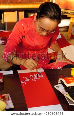 HO CHI MINH CITY, VIET NAM- FEB 7: Atmosphere of springtime with colorful scene, Vietnamese woman in ao dai, write chinese writing or calligraphy at spring fair on Tet, Vietnam, Feb 7, 2015