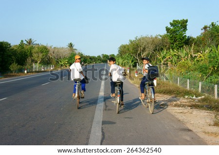 BEN TRE, VIET NAM- MAR 24: Group of three unidentified Asian pupil ride bicycle on country road to go to school, boys in uniform, happy with friendship, Vietnam, Mar 14, 2015