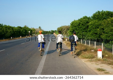 BEN TRE, VIET NAM- MAR 24: Group of three unidentified Asian pupil ride bicycle on country road to go to school, boys in uniform, happy with friendship, Vietnam, Mar 14, 2015