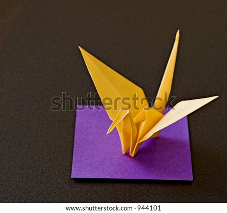 Origami paper crane set on a purple square with black background