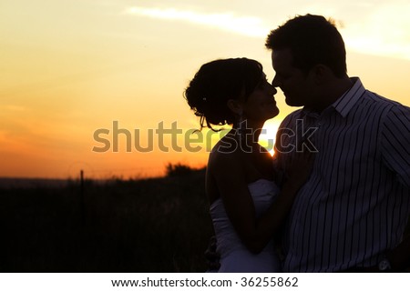 Bridal couple in the field as the sun sets