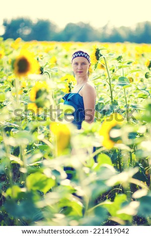 Young woman in ethnic clothes enjoys her time on sunflower field