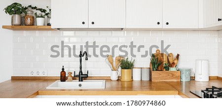 Banner View on white kitchen in scandinavian modern style, kitchen details, plants on wooden table, white ceramic brick wall background. Sustainable living eco friendly kitchen.