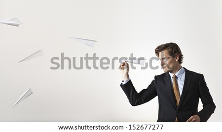 Focused businessman throwing lots of paper planes