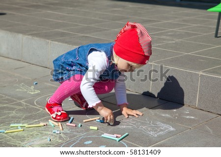 little girl drawing on sidewalk color chalks