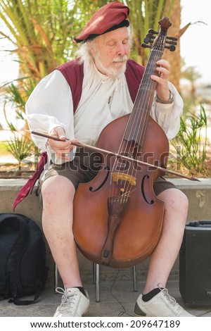 BOGOTA, COLOMBIA - APRIL 06, 2014: An unidentified musician playing cello for money in the streets of Usaquen in Bogota Colombia. Usaquen was declared a national monument in 1987.