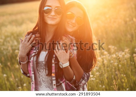 Two happy girls hugging outdoors.  Strong glare of sun