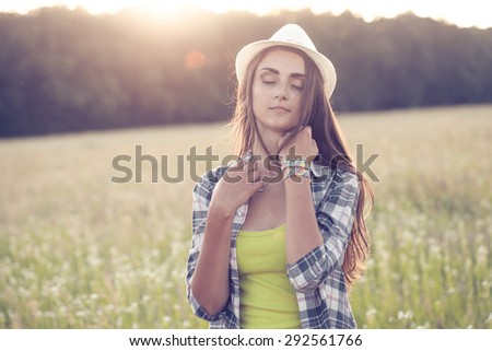 Beautiful young woman in hat outdoors at  sunset. High Key