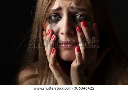 Crying young woman on a black background. Closeup