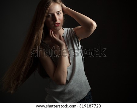 Young woman in a torn shirt on black background