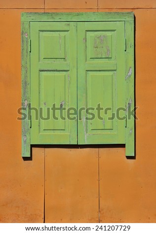 Old sealed wooden window. Wooden green window on orange wall is closed.