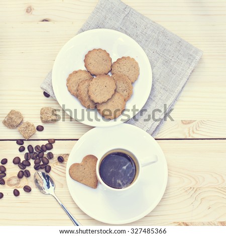 Ginger biscuits, cinnamon, a cup of hot coffee. Walnuts, hazelnuts on a wooden background. Toned photo.
