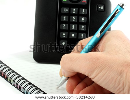 Hand writes a pen on an empty paper and black telephone