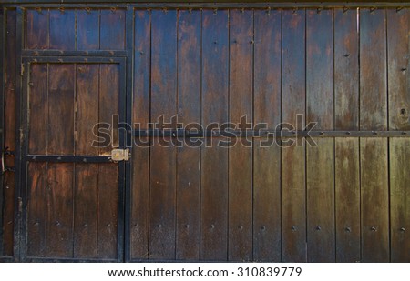 Old wooden gate with a walk through door.  Iron frames the old wood.