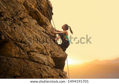 Beautiful Woman Climbing on the High Rock at Foggy Sunset in the Mountains. Adventure and Extreme Sport Concept Сток-фото © 