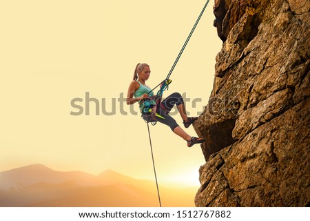 Beautiful Woman Climbing on the High Rock at Foggy Sunset in the Mountains. Adventure and Extreme Sport Concept 商業照片 © 