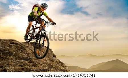 Cyclist Riding the Bike Down the Rock at Sunrise in the Beautiful Mountains on the Background. Extreme Sport and Enduro Biking Concept. Imagine de stoc © 