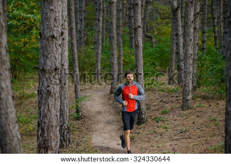 Young Man Running on the Trail in the Wild Pine Forest. Active Lifestyle Concept