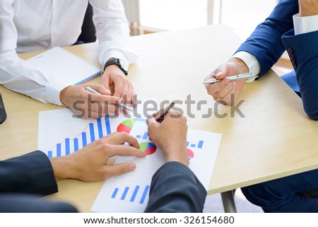 Business People Analyzing Financial Results on Graphs around the Table in Bright Modern Office. Team Work Concept