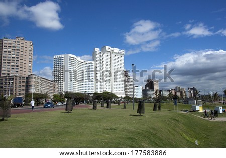 DURBAN, SOUTH AFRICA - DECEMBER 6, 2013: Pedestrians and cyclists on grassy banks in front of residential and commercial buildings on the beachfront \