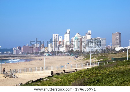 DURBAN, SOUTH AFRICA - MAY 24, 2014: Dune vegetation and many people on beach with Durban city skyline in South Africa