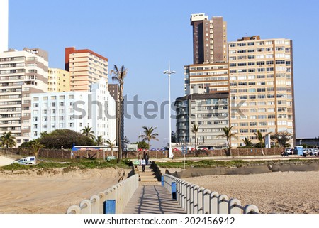 DURBAN, SOUTH AFRICA - JULY 2, 2014: Three unknown people enter onto pier in front of residential complexes in beach front in Durban, South Africa