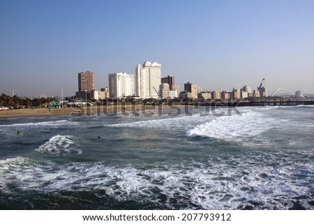 DURBAN, SOUTH AFRICA - JULY 23, 2014: Early morning view of people, surfers,  ocean, beach and city skyline in Durban, South Africa