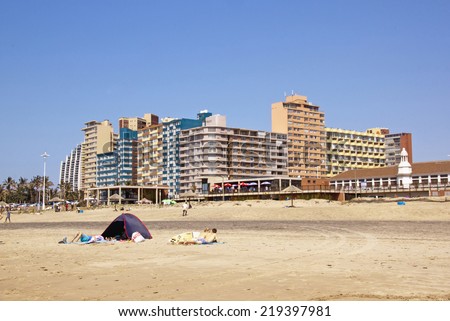 DURBAN, SOUTH AFRICA - SEPTEMBER 21, 2014: Many unknown people and tent on beach in front of residential and commercial buildings on \