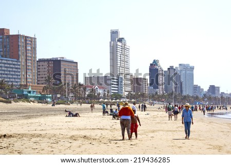DURBAN, SOUTH AFRICA - SEPTEMBER 21, 2014: Many unknown people enjoy early morning sunshine against city sky line in Durban, South Africa