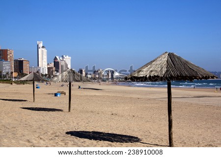 DURBAN, SOUTH AFRICA - DECEMBER 18, 2014: Three wooden sunshades and many unknown people on Addington Beach in Durban, South Africa