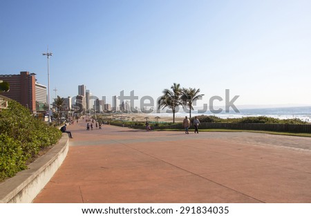 DURBAN, SOUTH AFRICA - JUNE 7, 2015: Many unknown people walk along Beach front promenade against Durban City skyline in South Africa