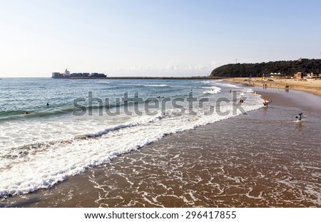 DURBAN, SOUTH AFRICA - JUNE 7, 2015: Many unknown people on Vetch\'s beach and ship entering in harbor in Durban, South Africa