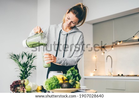 Young Woman Making Detox Smoothie At Home. Woman pouring smoothie to glass. healthy food concept