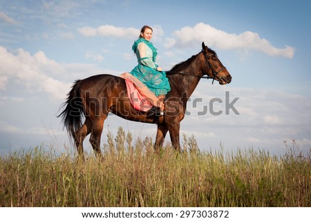 Horsewoman in blue dress on the blue sky background