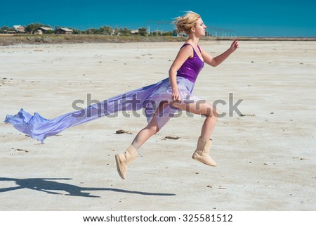 Woman in violet dress runs across white ground