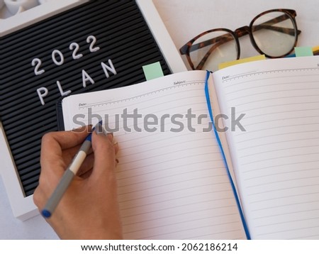 2022 New year resolution office concept on yellow desk with notebook ,office accessories and money. Goal list 2021 with change and determination concept. 2021 budgeting.