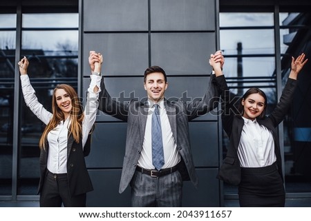 Photo of three  happy young  businesspeople in formal wear celebrating, gesturing, keeping arms raised and expressing positivity. ストックフォト © 