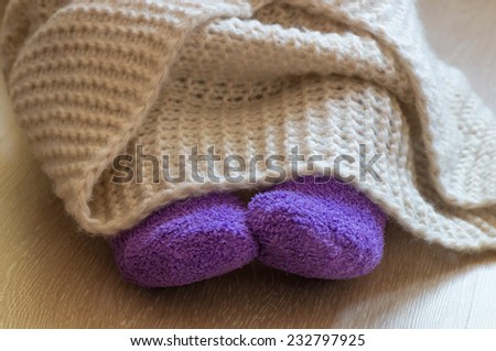 Cold concept fluffy warm purple sock on the feet and fluffy warm blanked on the legs