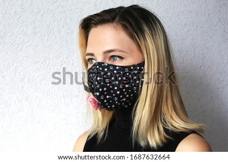 Woman wearing cloth cotton face mask decorated with flowers. Stylish handmade cotton mask. Designed reusable face mask.