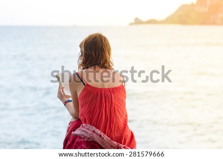 Hands of woman holding a book read beside the sea