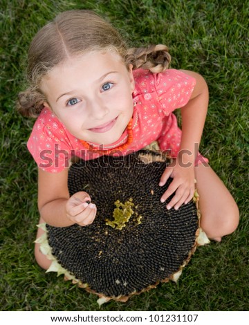 Rest in the garden - adorable girl with the seeds of the sunflower
