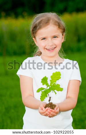 Environmental protection - lovely girl and young plant of a oak