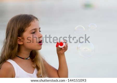 Children\'s games - young girl playing with soap bubbles, happy summer