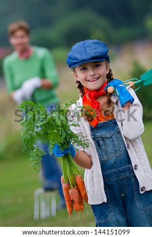Gardening, harvest, cultivation -  girl with bunch of carrots in vegetable garden