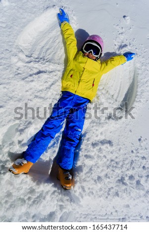 Winter fun - Snow Angel - young skier girl playing in snow